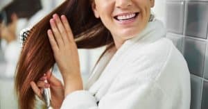 Mujer cepillando suavemente su cabello, representando los cuidados diarios para un pelo sano.