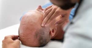 Médico examinando el cuero cabelludo de un paciente, ilustrando cómo aumenta la demanda de injertos capilares en España.