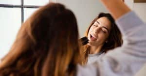 Mujer disfrutando de su rutina diaria mientras cuida su melena, un gesto asociado a cómo fortalecer el pelo.