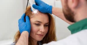 Médico examinando el cuero cabelludo de una mujer durante una consulta para injerto capilar, ilustrando alternativas a Turquía para trasplante capilar femenino.