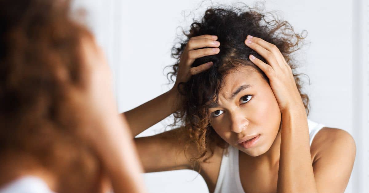 Persona revisando su cuero cabelludo ante la clara evidencia de problemas capilares o problemas del cuero cabelludo.