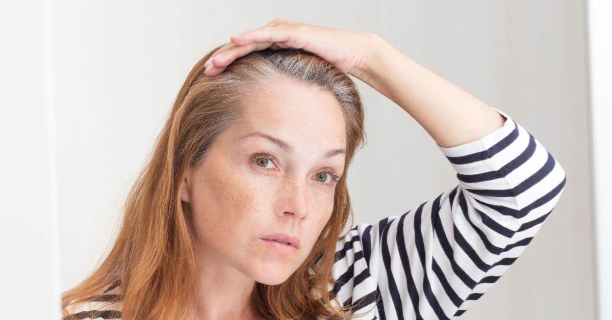 Mujer revisando su raíz capilar y la densidad de su pelo, ilustrando la preocupación de tener el cabello muy fino y poca cantidad.